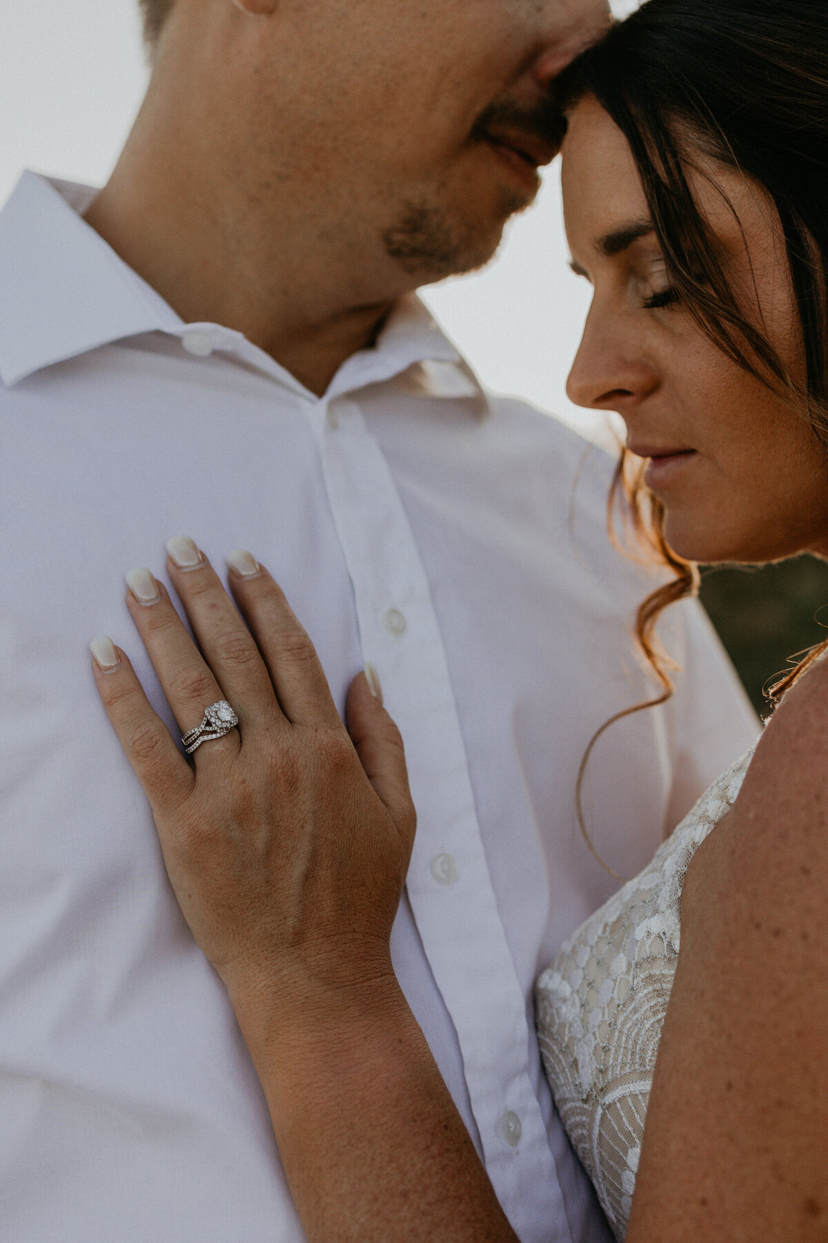 close up on a brides hand against her grooms chest focusing on the ring