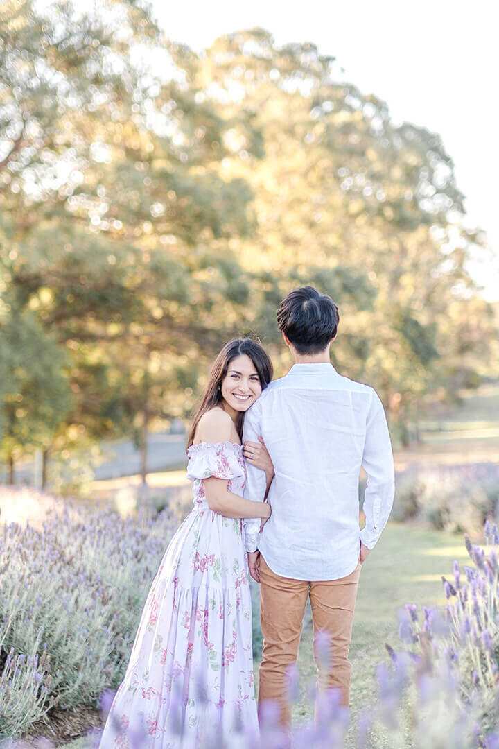 couple hugging in sirromet lavender field having fun with Hikari’s engagement session
