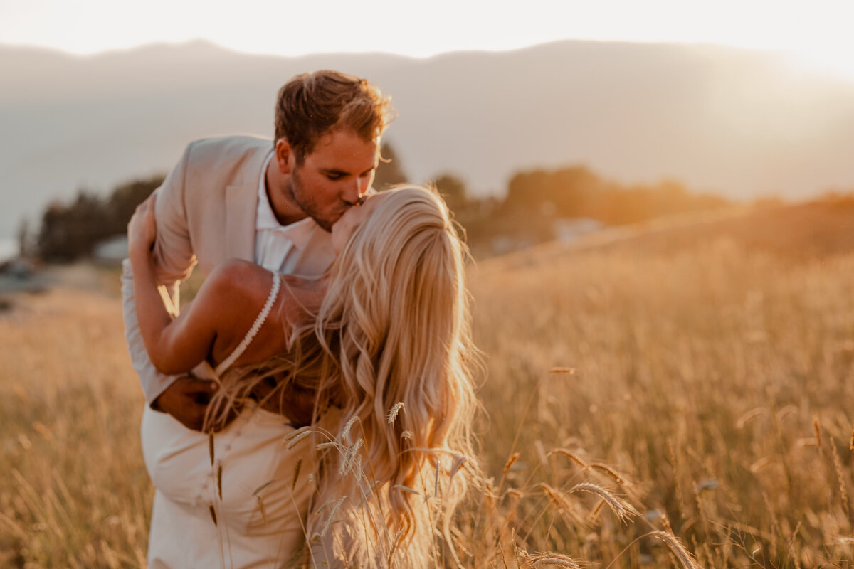 The groom kisses the bride as thee sun sets during their wedding in Chelan, Washington.