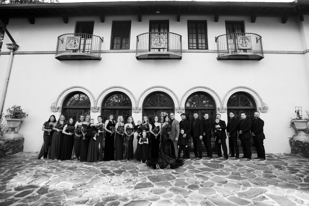Black and white photo of a large wedding party pose at Rushmore Estate wedding photographer Milestone Images