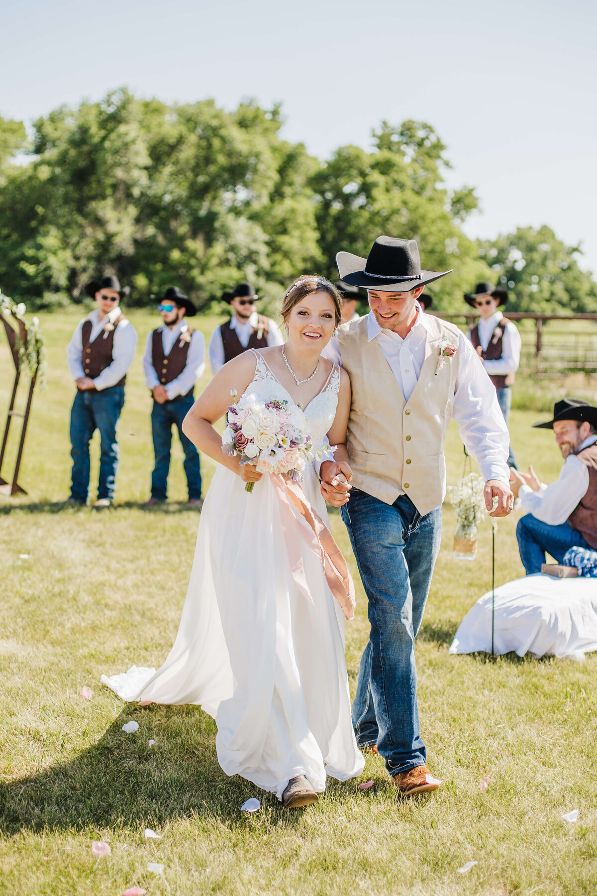 Bride and groom walk out of their ceremony holding hands and bouquet.