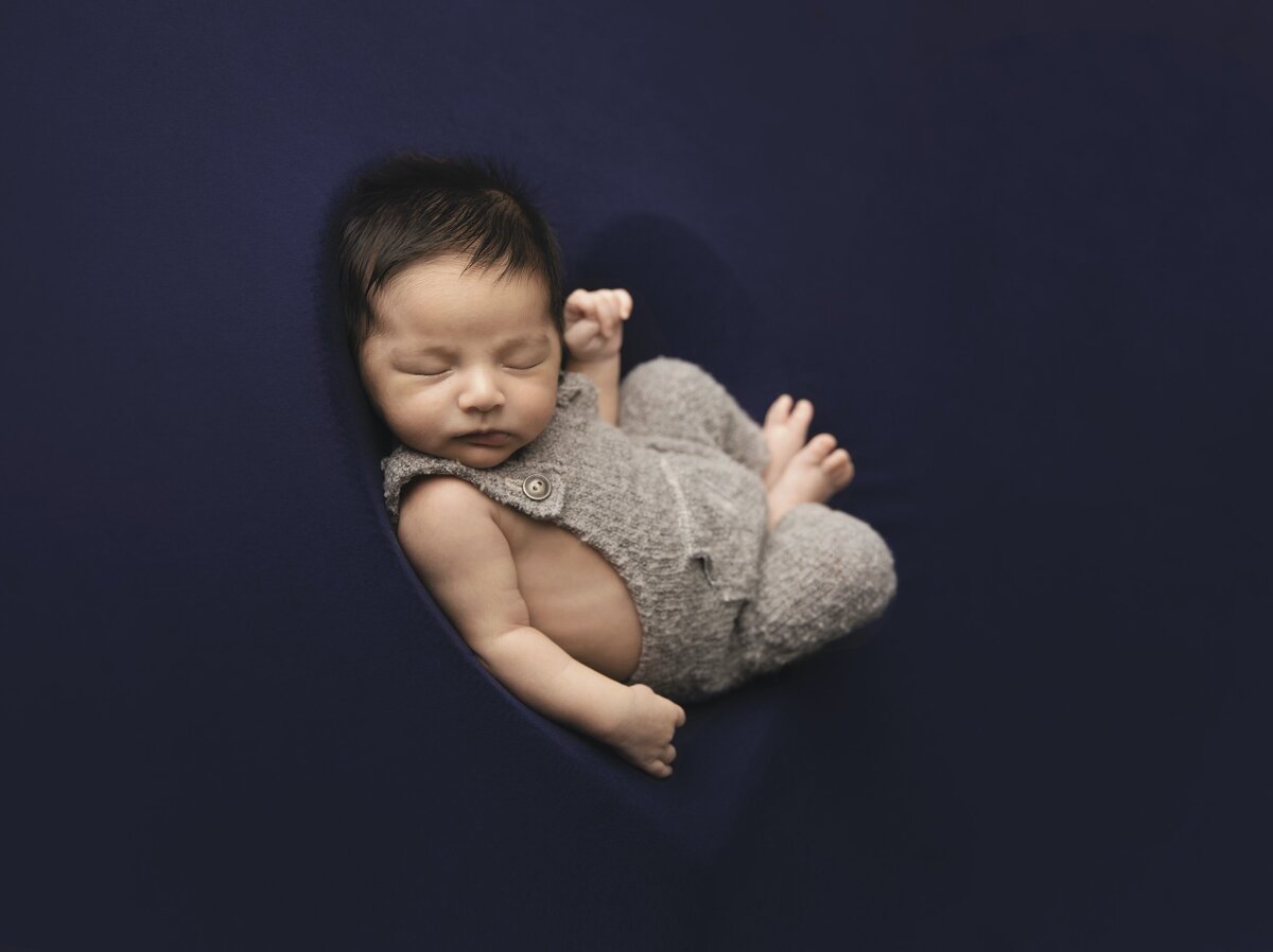 Newborn in knit jumper on blue background