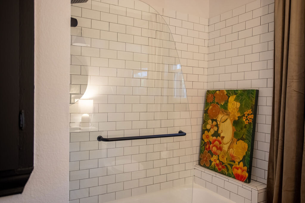 Subway tile shower in the bathroom of this three-bedroom, two-bathroom mid-century house that sleeps 8 and boasts a unique experience in color, style, and lifestyle products located in the heart of Waco, TX.