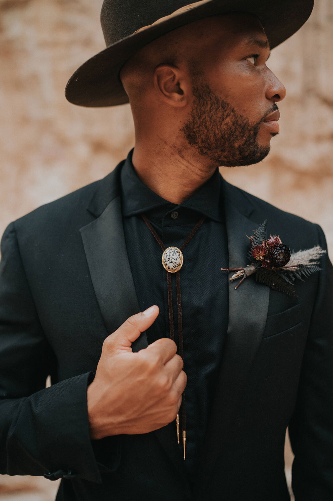 Black groom wearing a black suit and hat