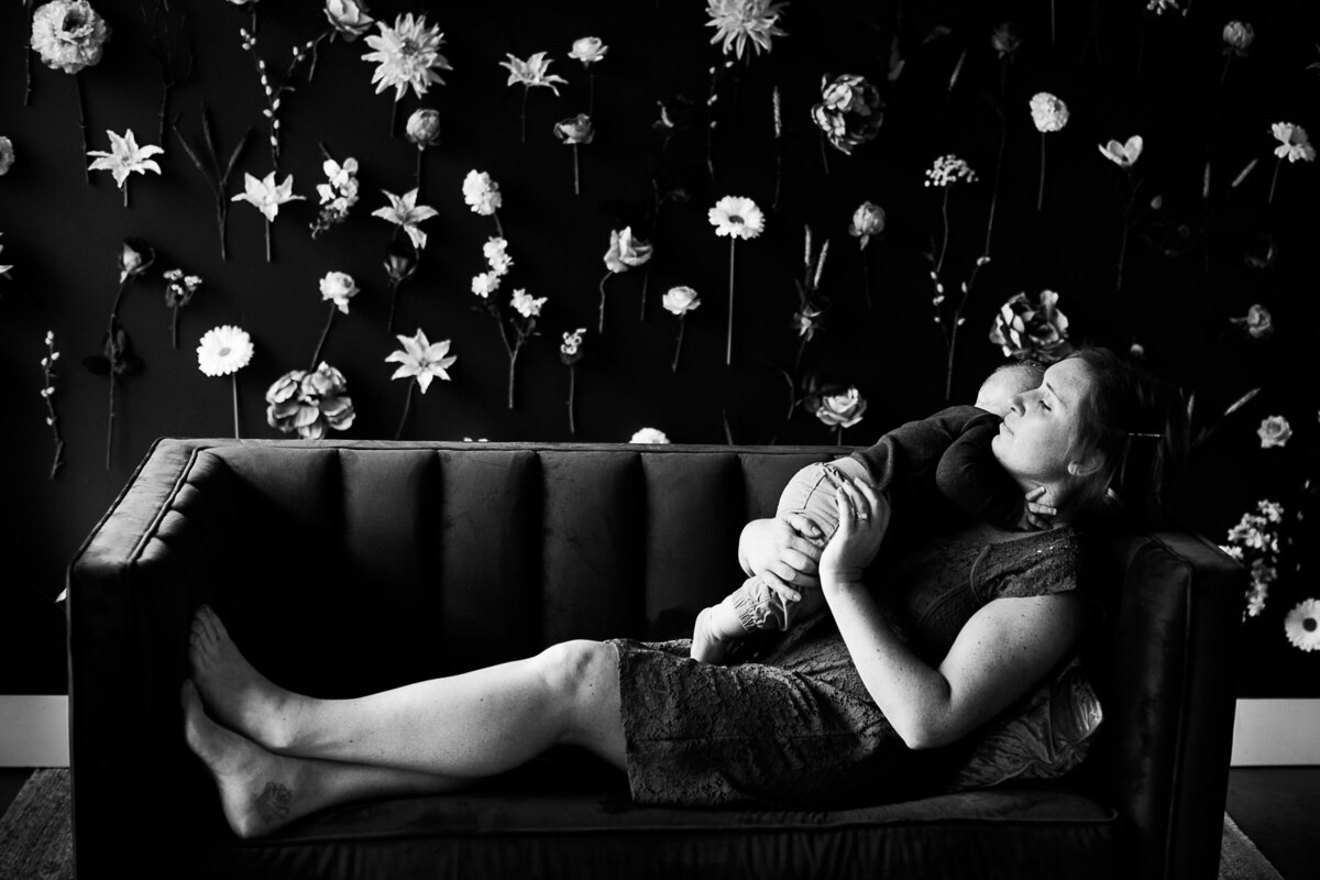 black and white photo of a mom holding her son while she sits on a couch