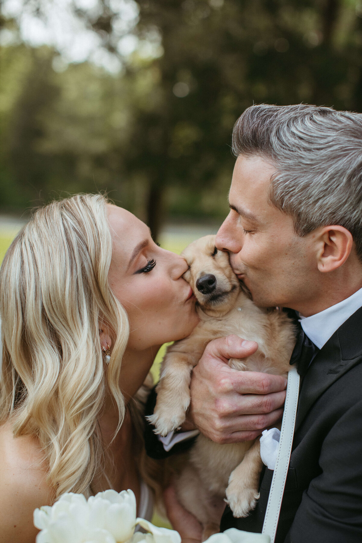 Bride and groom kiss dog