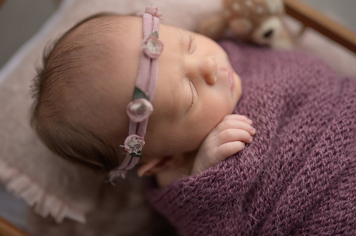 Newborn baby girl portrait in deep purple wrap