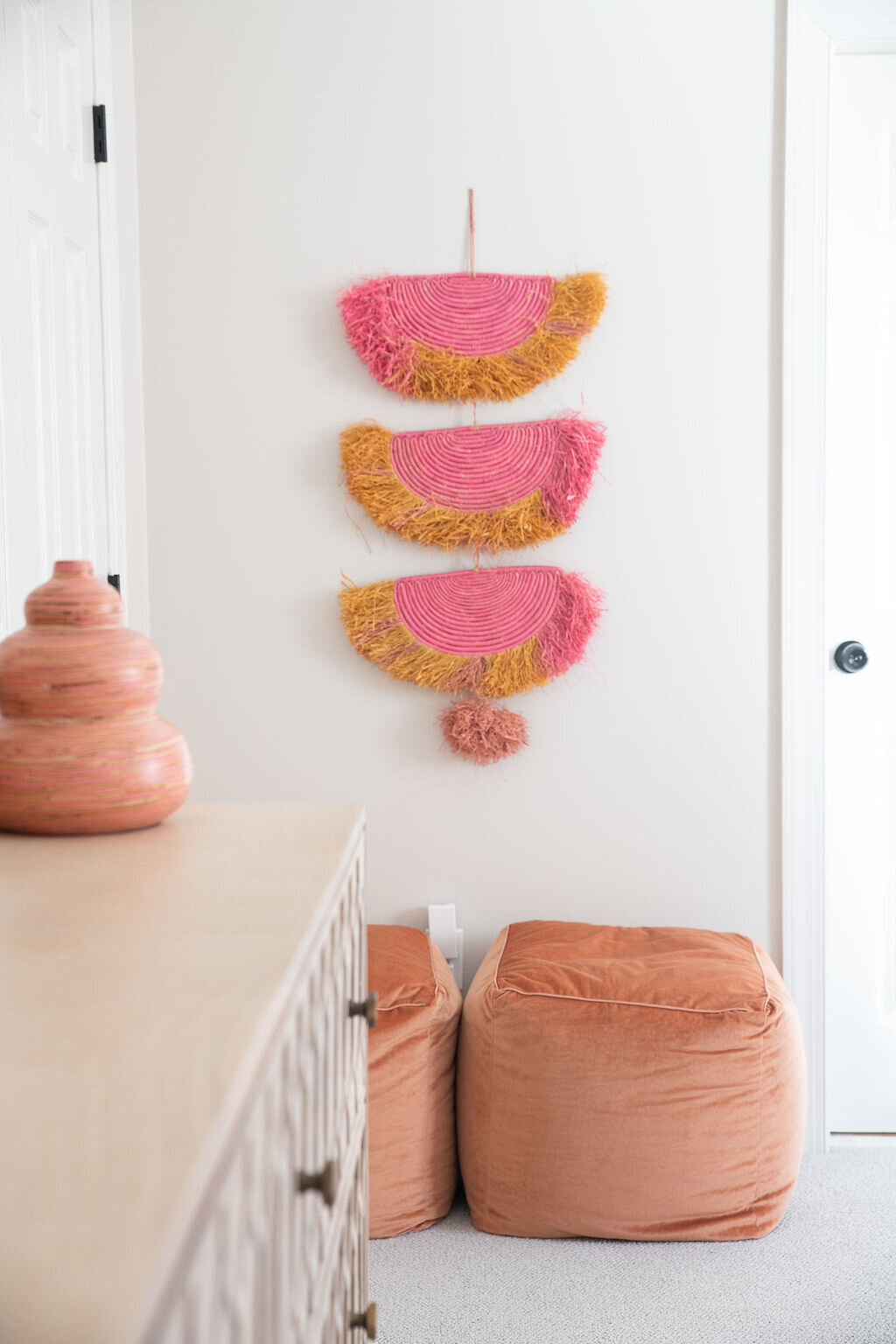 pink tassel wall art hanging in a kid's bedroom