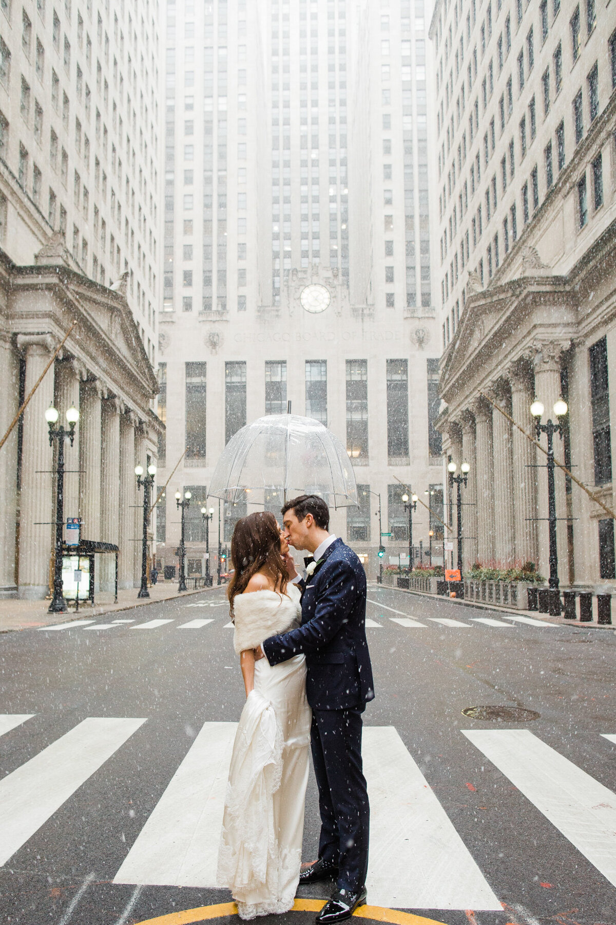 Newlyweds share a kiss in the snow on their wedding day in downtown Chicago