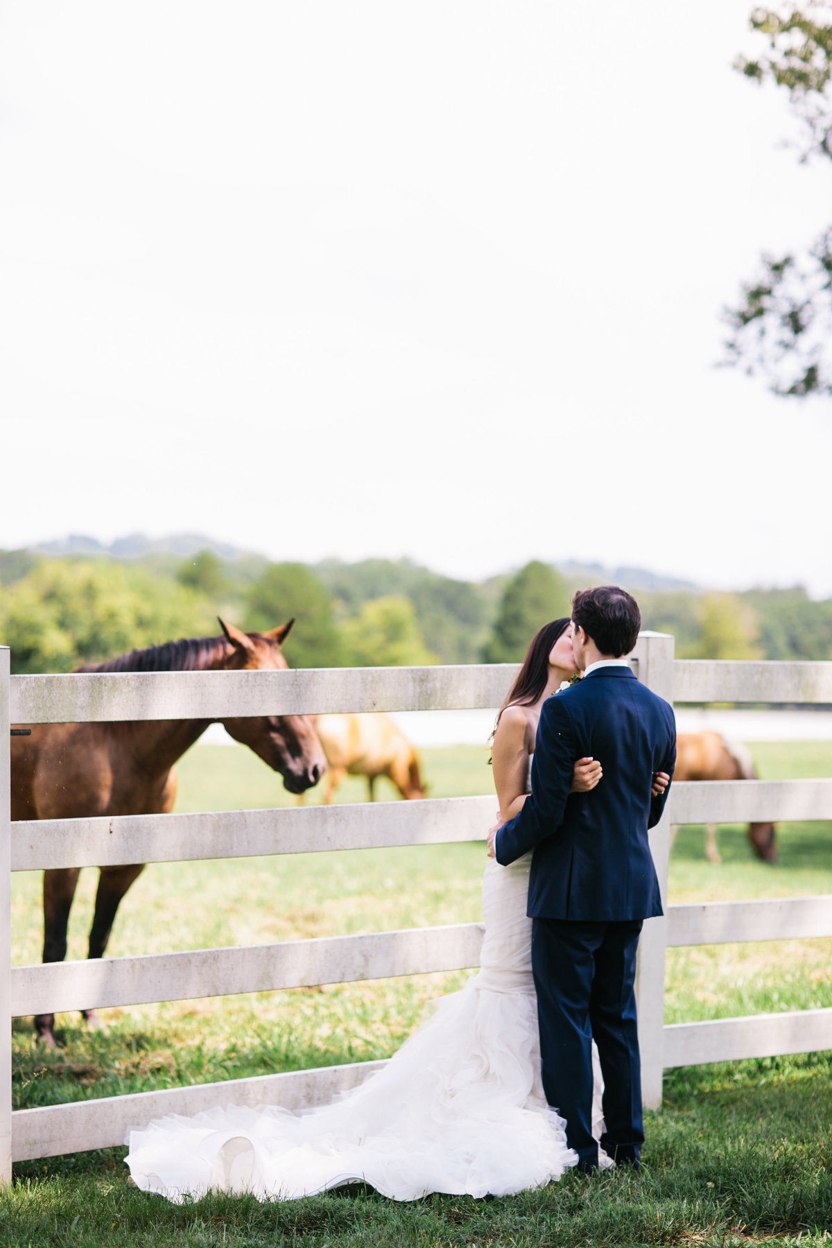 couple kissing by horses at wedding venue