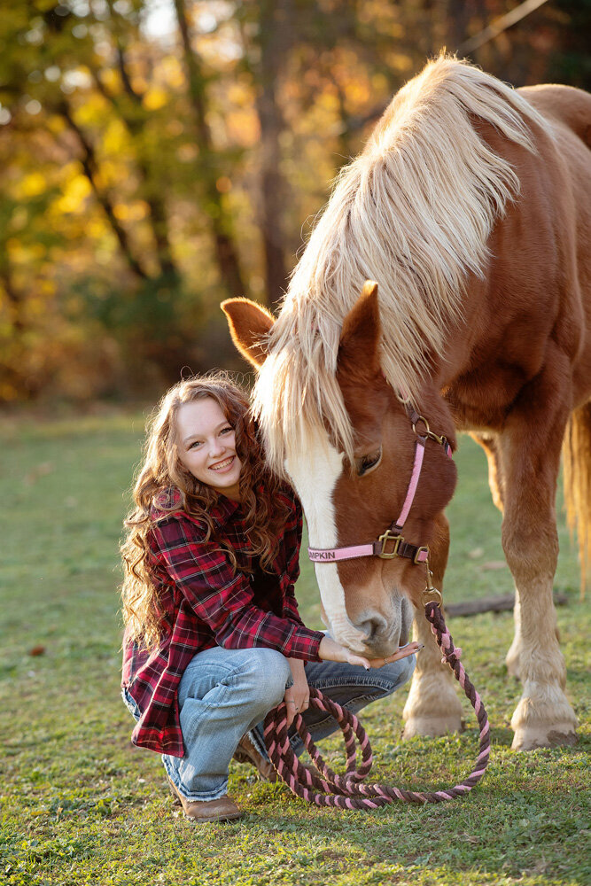 Senior session of young woman kneeling with a horse
