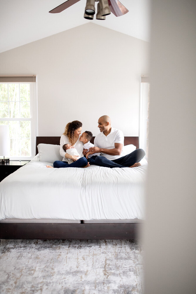 Newborn session in home with family sitting on the bed