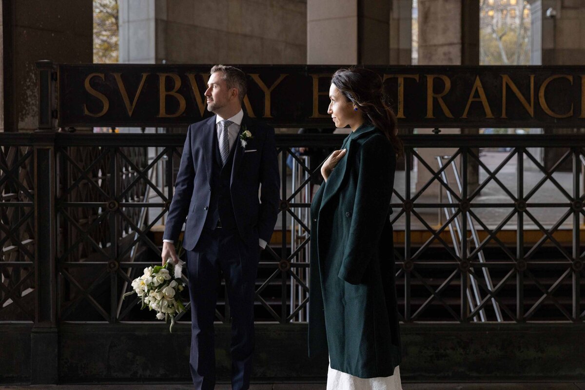 A wedding couple standing at the entrance to a subway station.