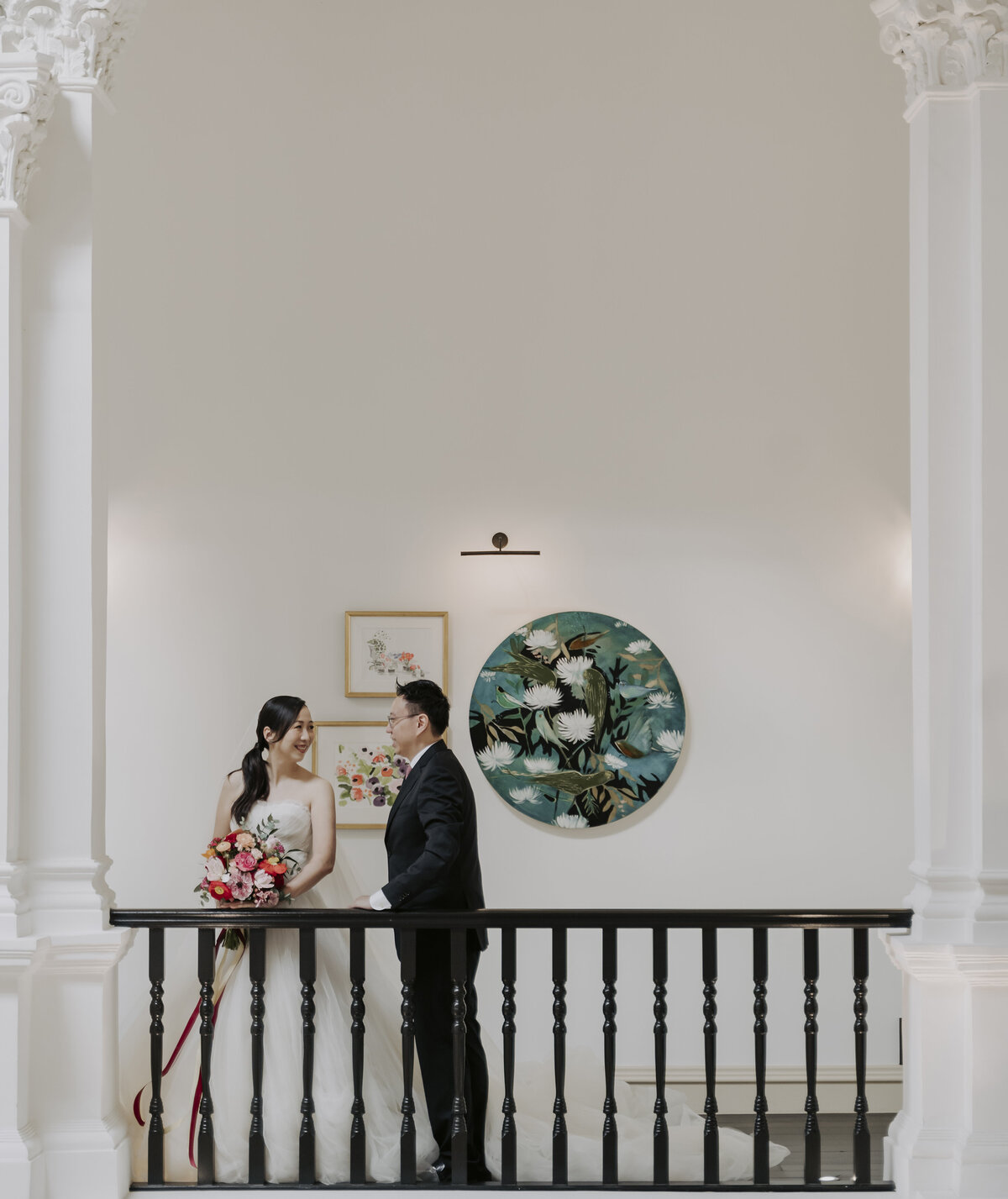 bride and groom laughing in front of artwork in the raffles hotel