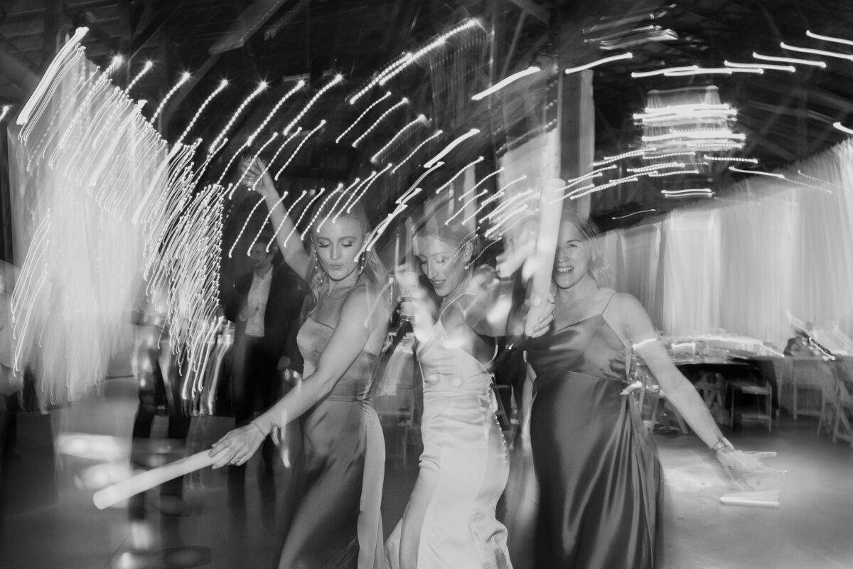 A bride and her bridesmaids dancing. Light trail reception candid captured by Fort Worth wedding photographer, Megan Christine Studio