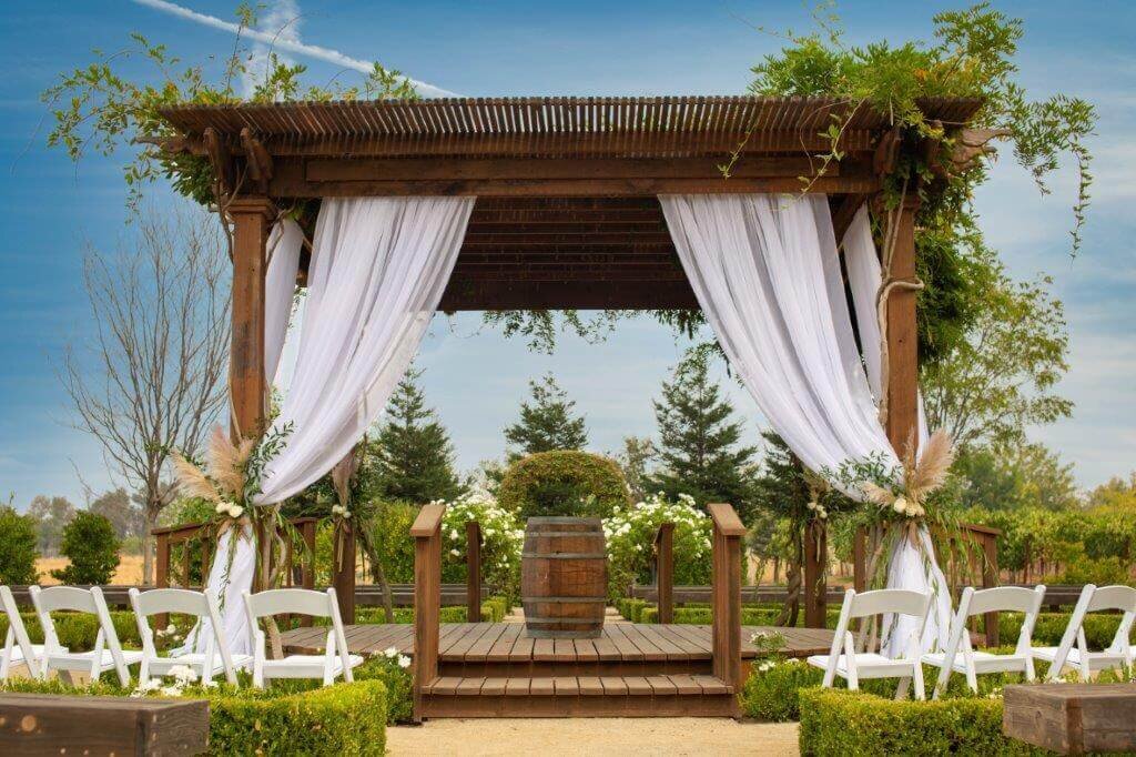 Wedding gazebo decorated with white linens and white chairs in the front at Wolf Heights Wedding venue in sacramento.