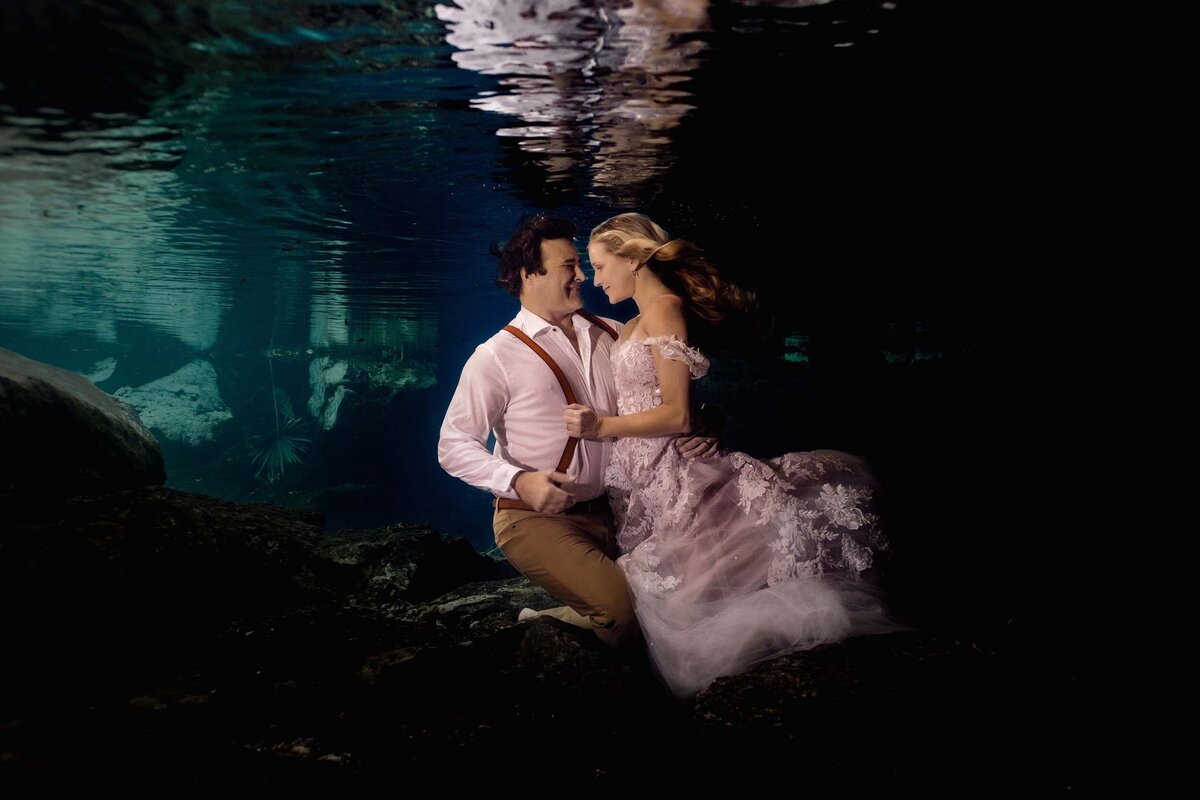 Bride pulling grooms suspenders in underwater Trash the Dress