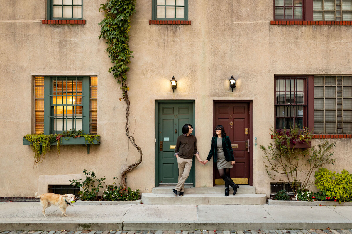 A couple leaning on a wall reaching out to hold hands.