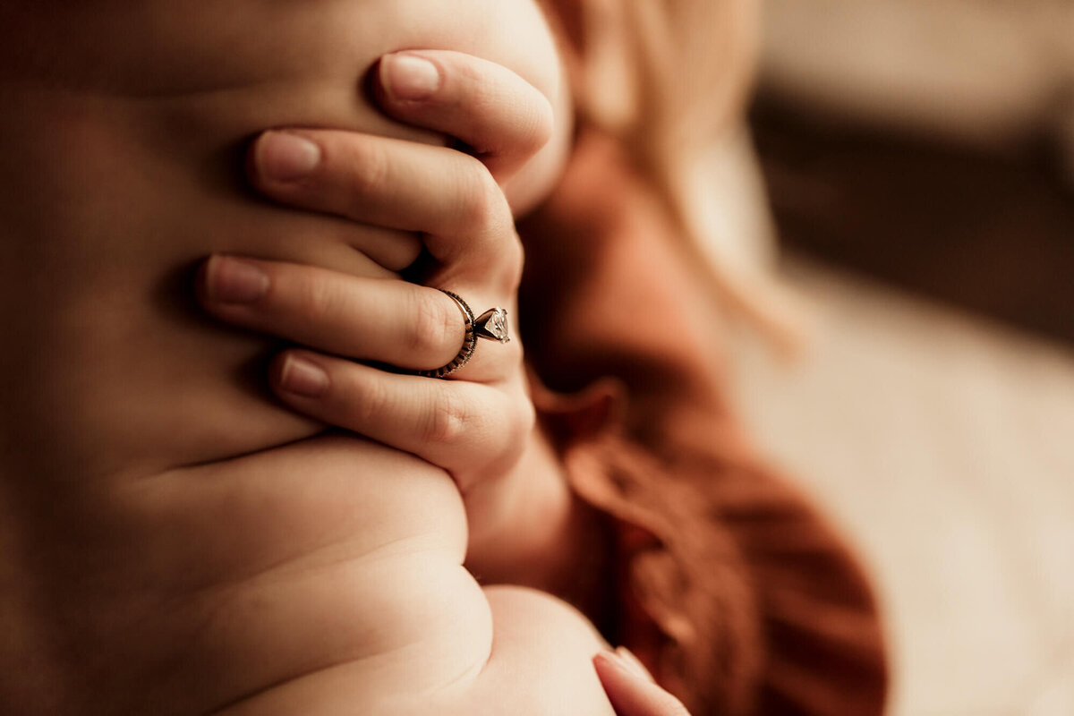 Mother's hand placed on her baby's side.