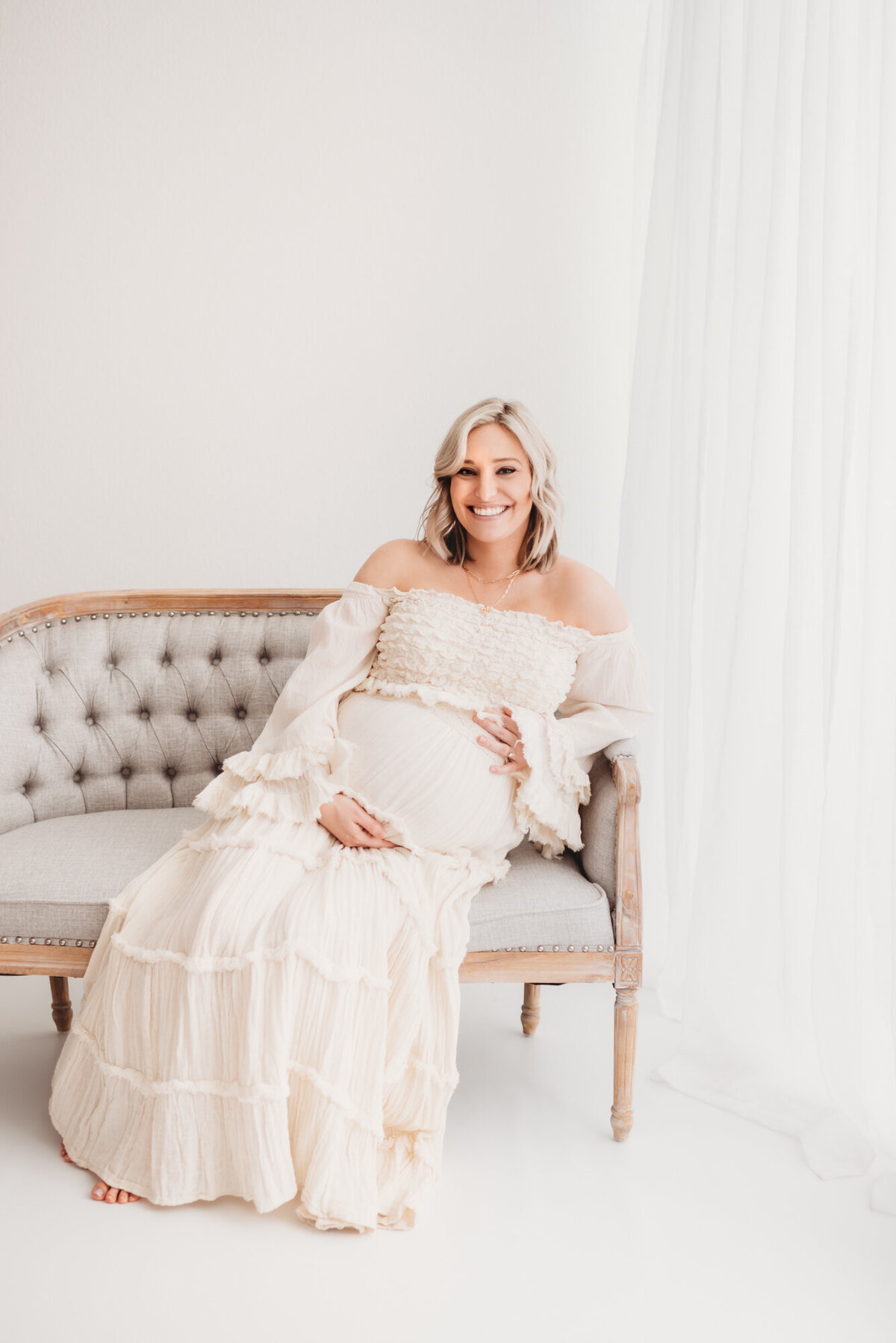 pregnant woman with denver maternity photographer sitting on classic couch