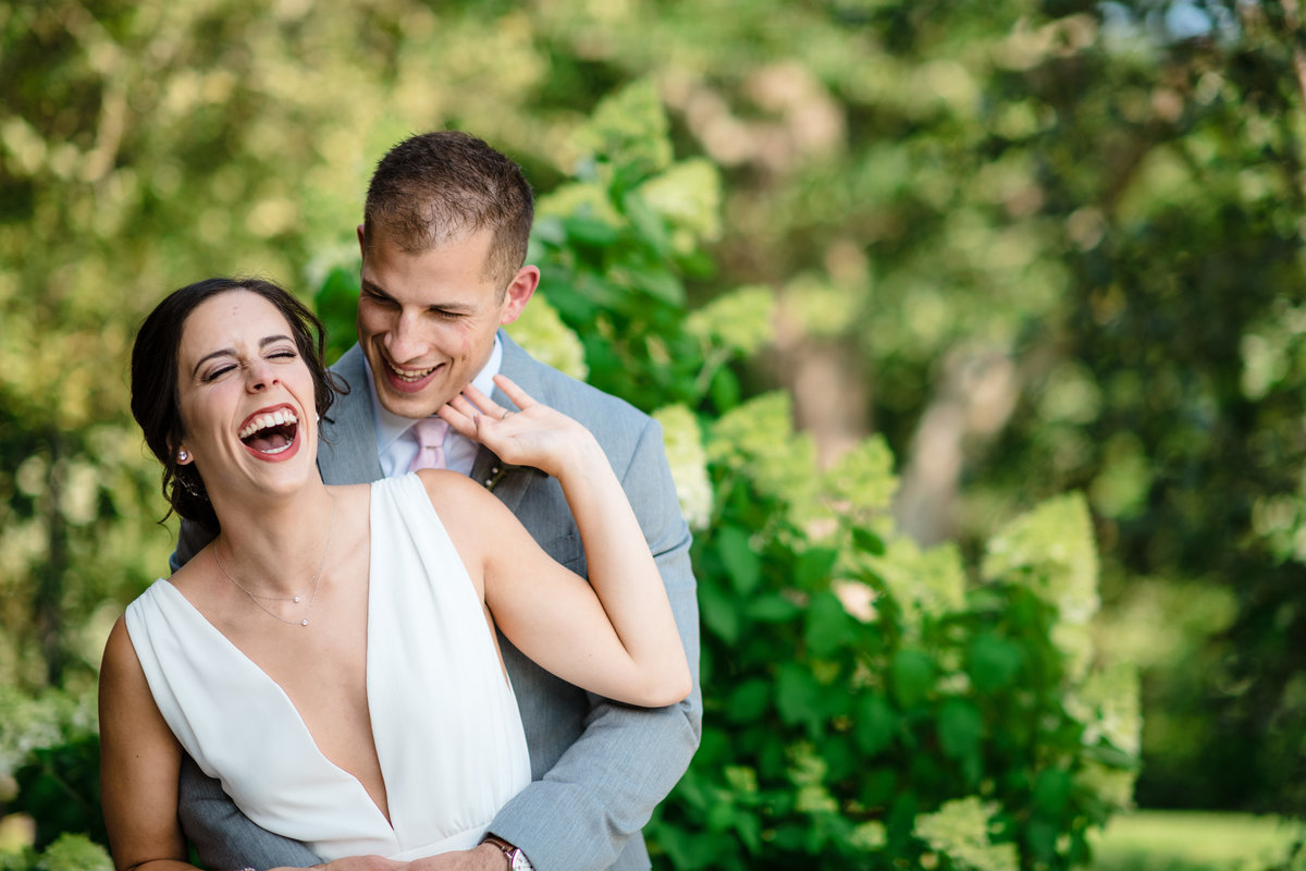 Bride and groom laugh together outdoors at their wedding at the barns at stonehurst hampton valley
