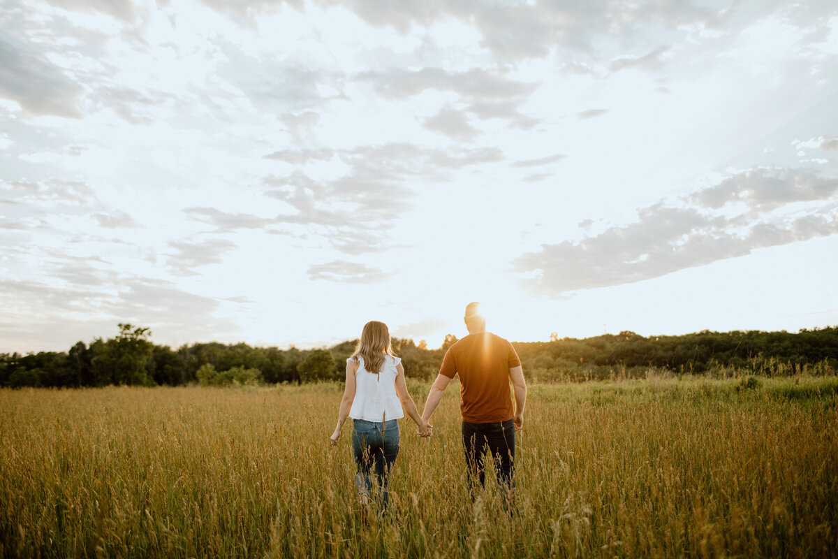 Couple walking into sunset in tall grass
