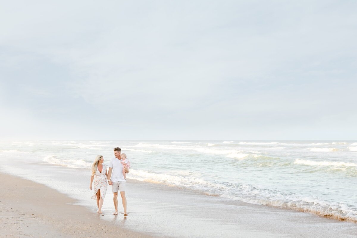 Couple and their baby walking along the beach holding hands