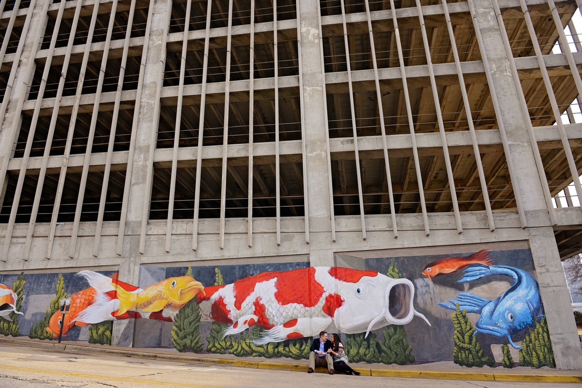 Couple cuddling by mural for downtown Huntsville engagement