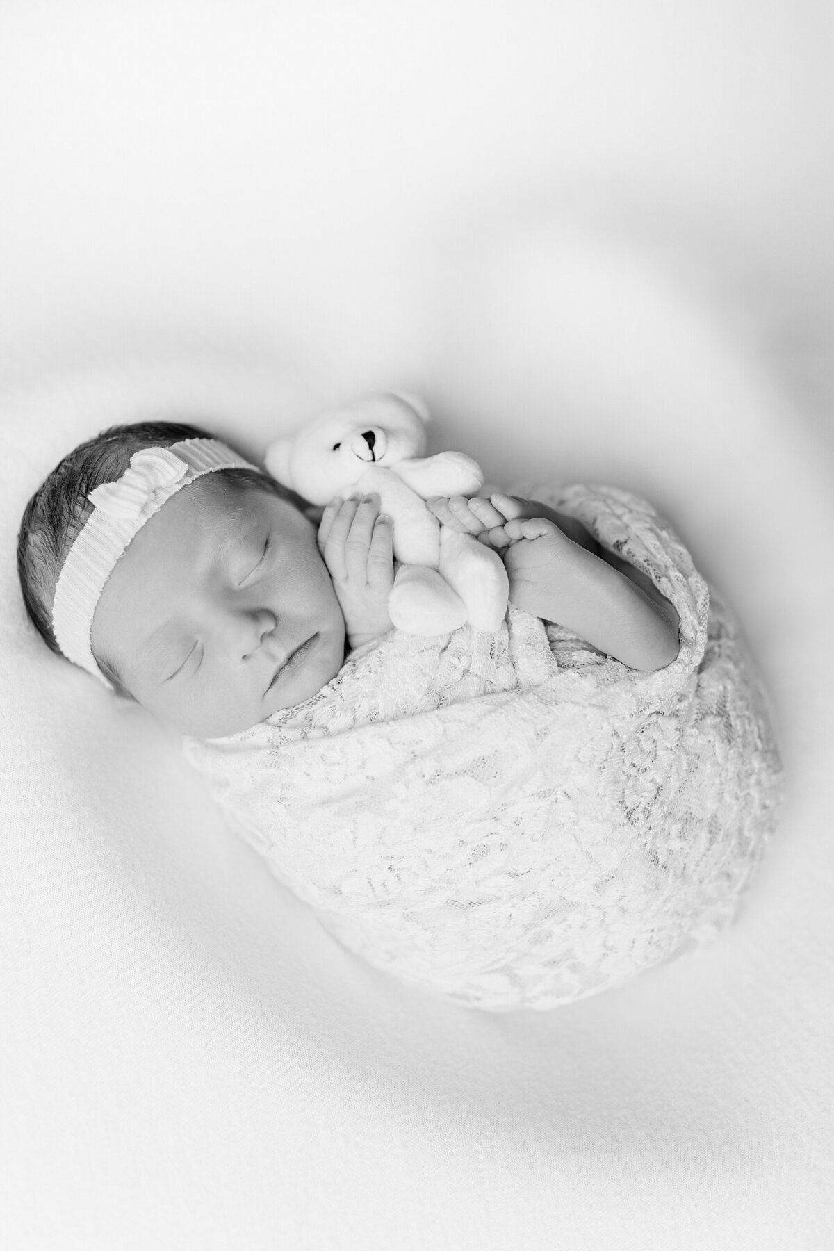 swaddled newborn girl holding a teddy bear