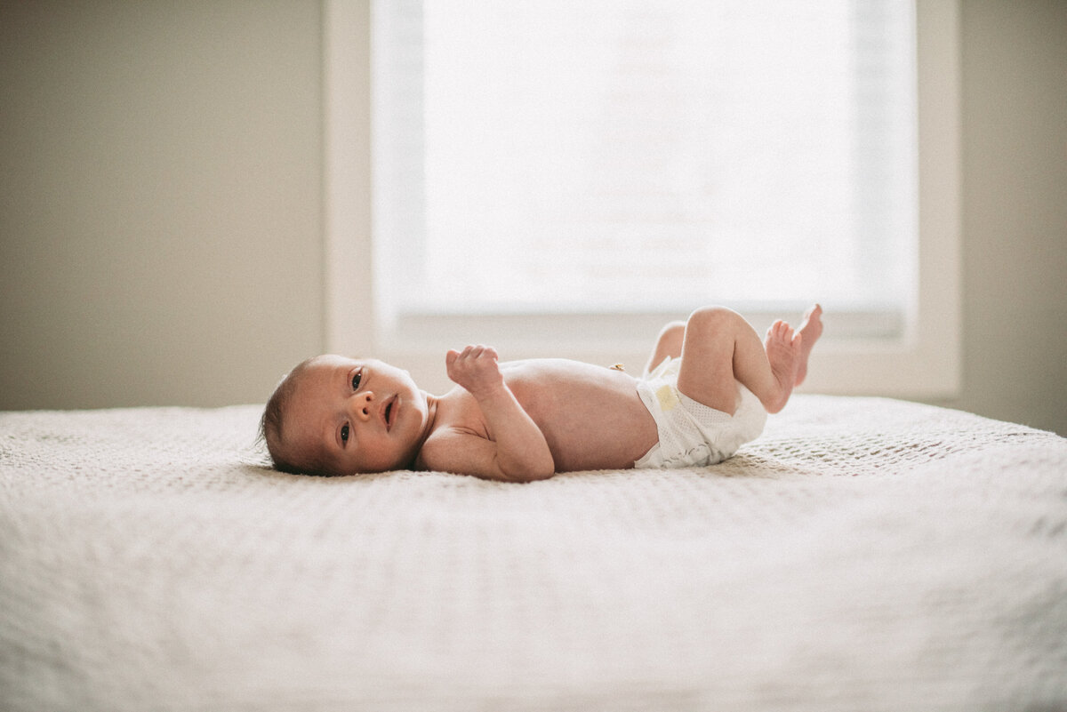newborn baby laying on bed