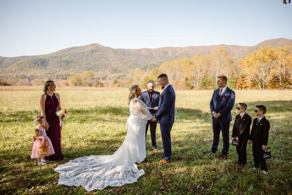 photographers in gatlinburg tn captures outdoor wedding ceremony at Cades Cove with couple holding hands and standing in front of their Gatlinburg officiant 