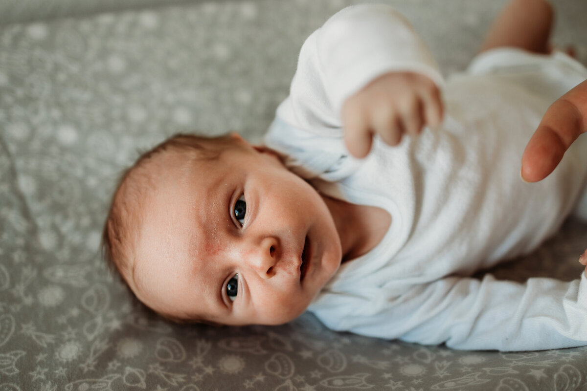 newborn baby boy stretches out in nursery