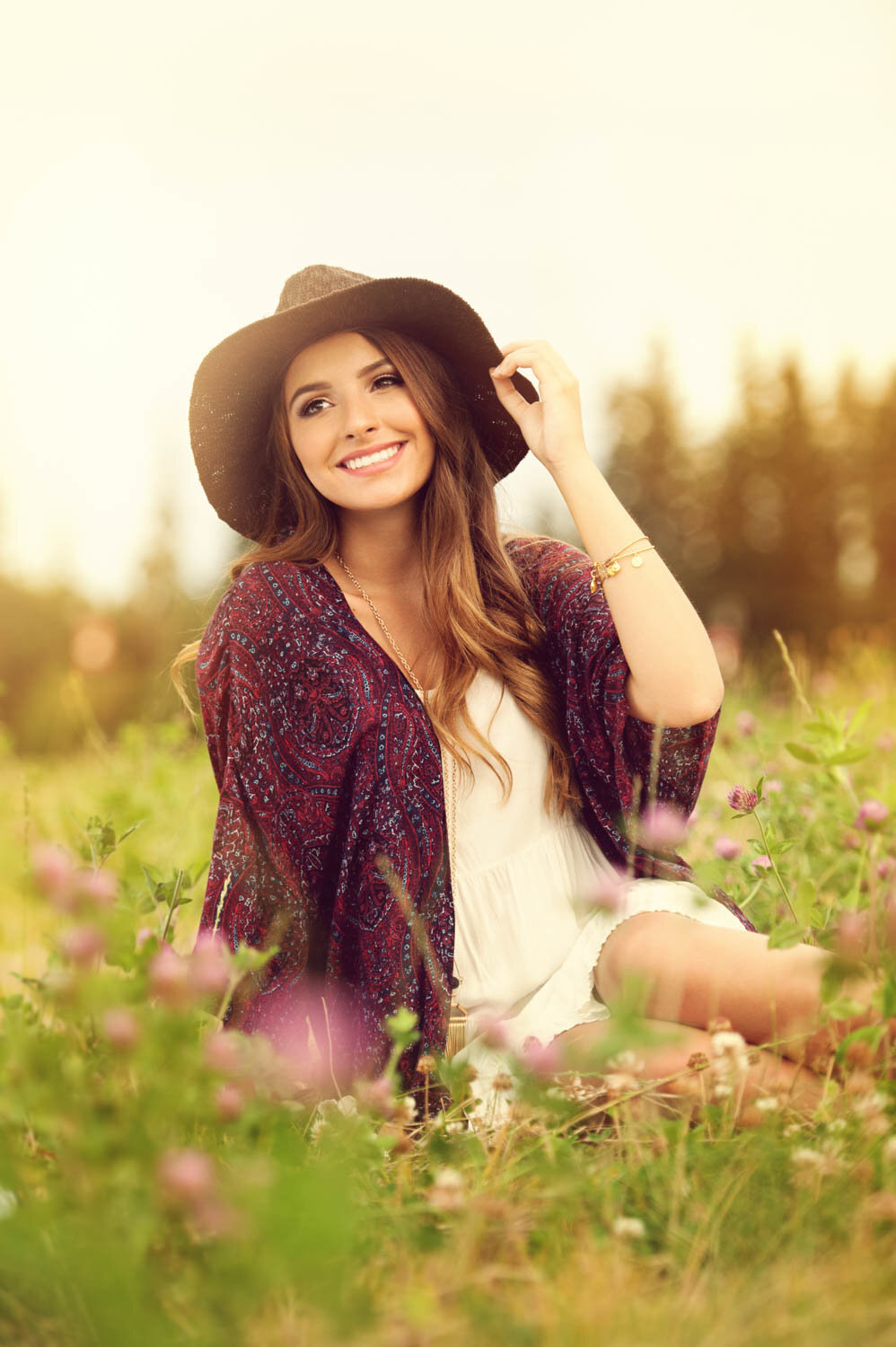 girl in blooming field with sun hat and patterned jacket