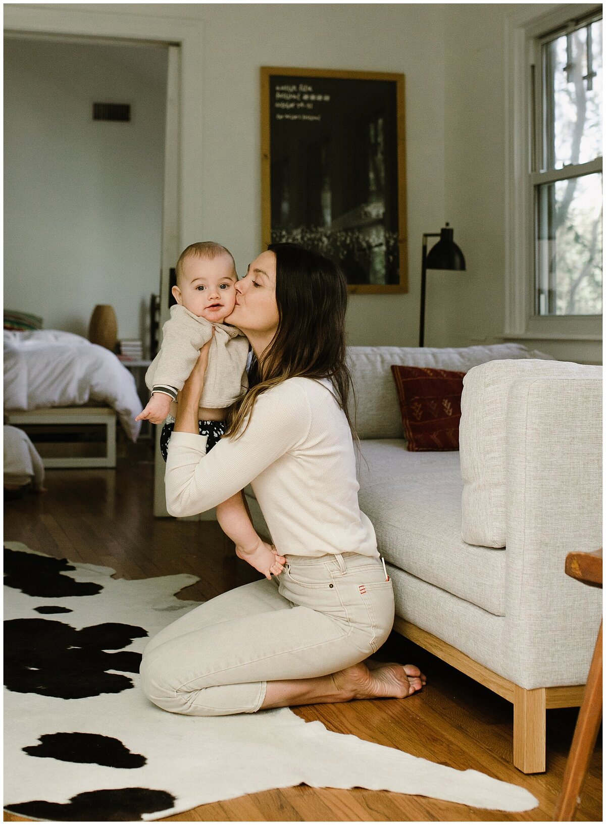 Mother kneeling on floor kissing baby at sweet home family session in Austin by Amber Vickey Photography