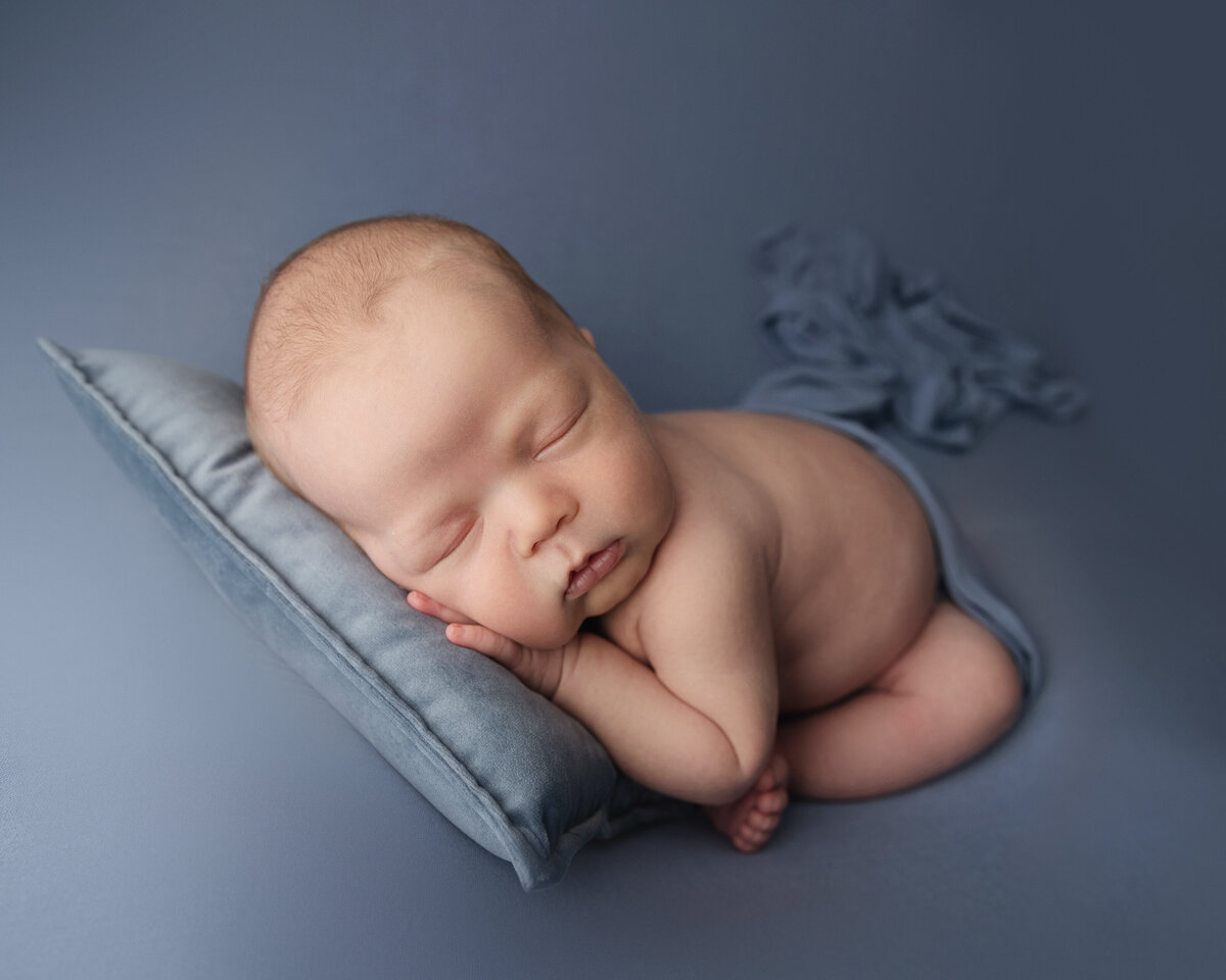 baby studio portrait image in blue with baby on pillow and wrapped in Greensburg studio