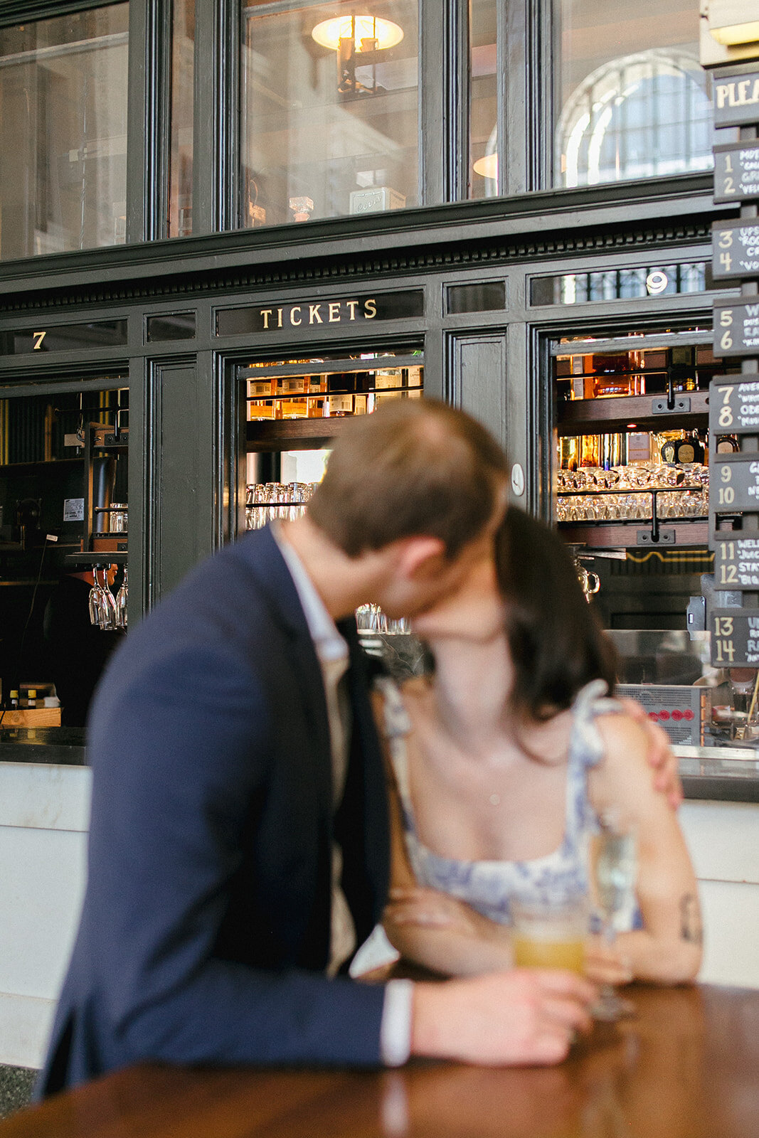 Couple kisses in front of the old ticket window, now called The Terminal bar, at Union Station in Denver, Colorado.