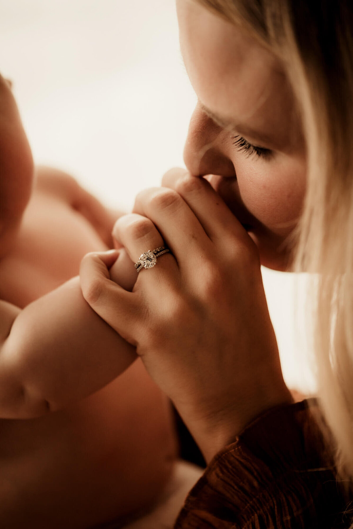 Mother kisses her baby's hand.