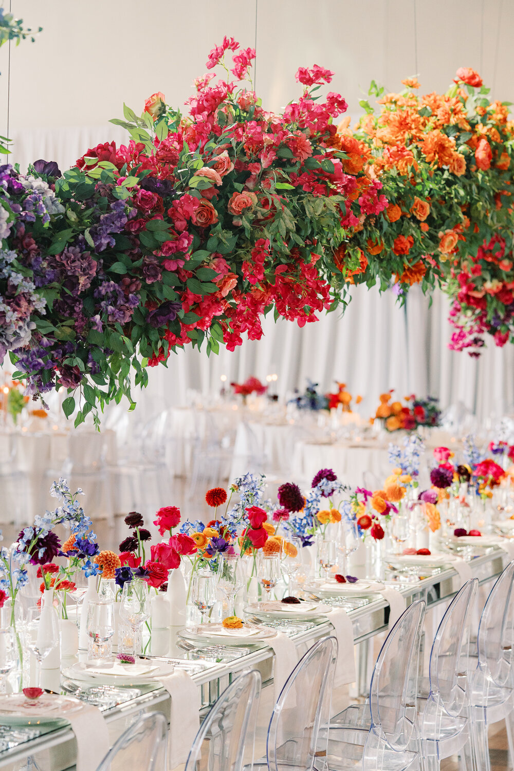 flower art installation over head table with colorful bud vases