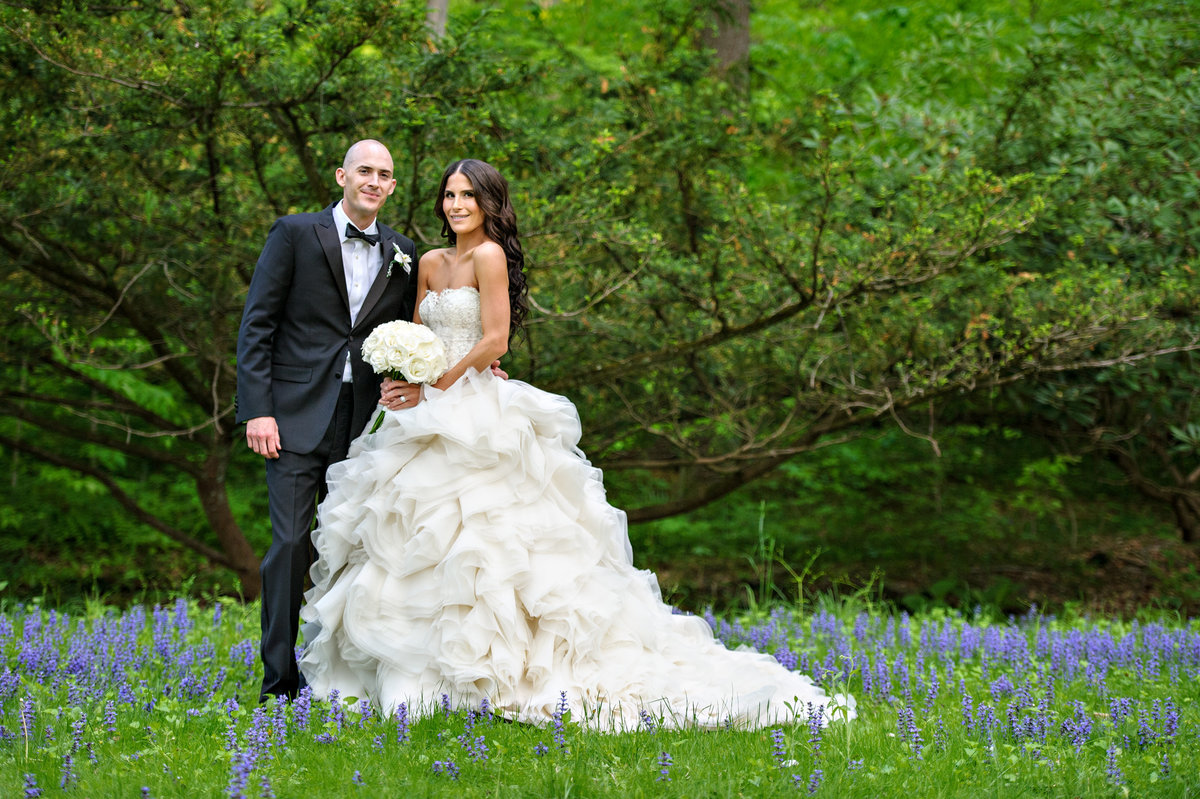 A wedding couple pose for a portrait in the flowers at Holly Hedge Estate.