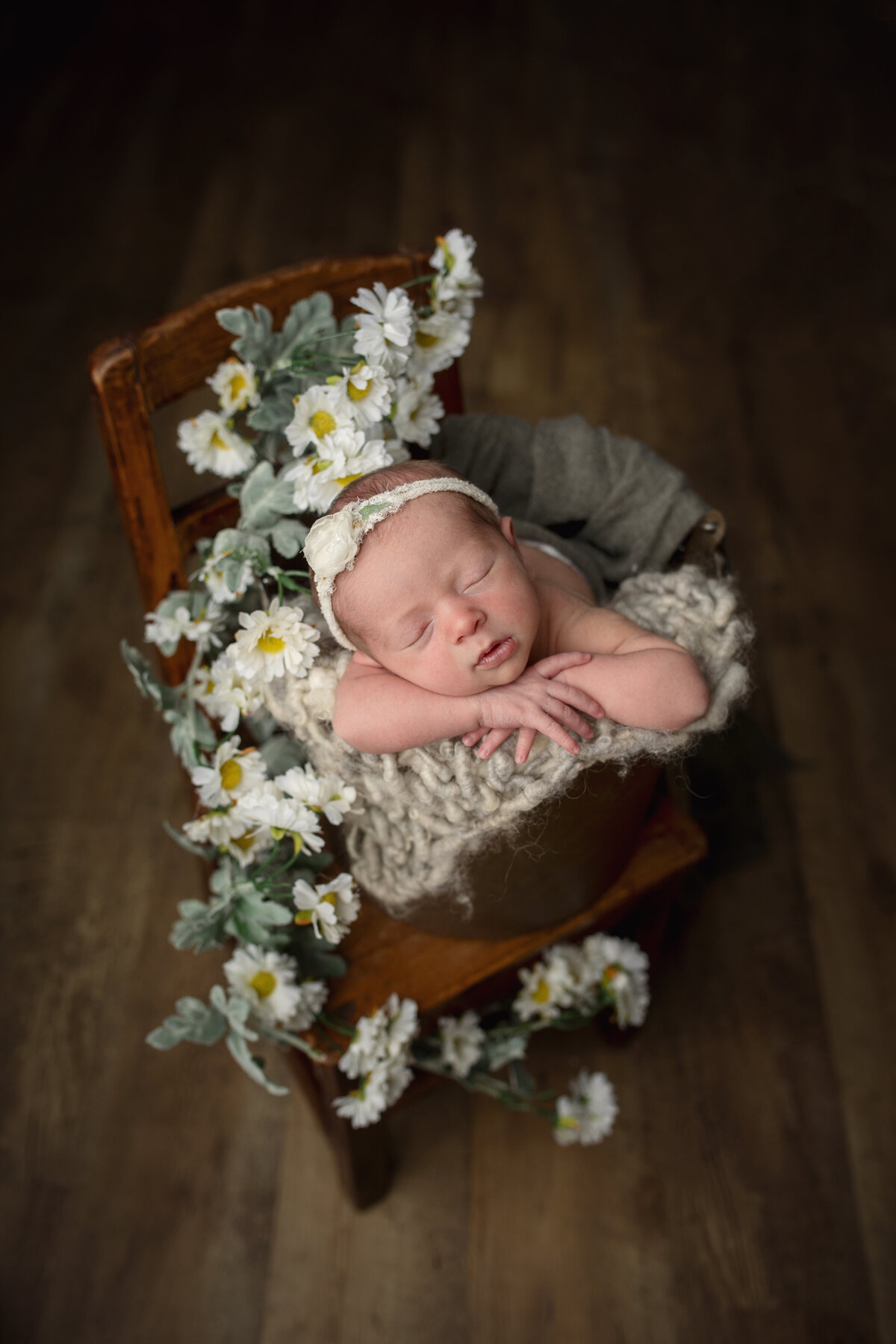 Newborn baby girl  posed in a bucket with flowers around her