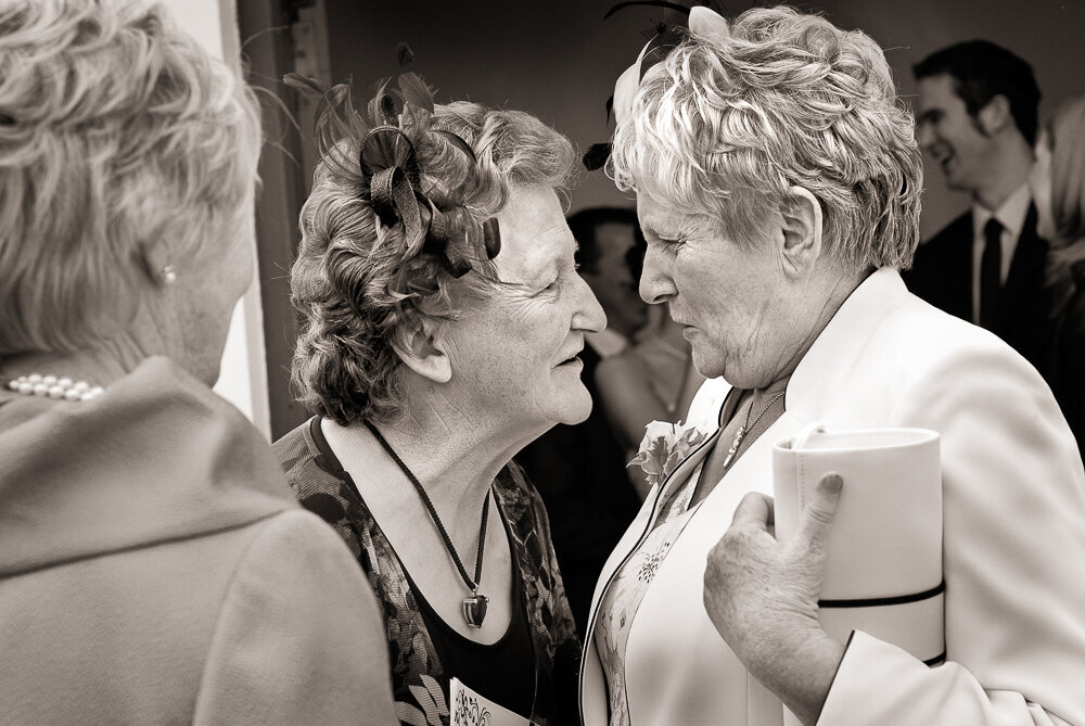 two female wedding guests in their fifties gossiping at a wedding