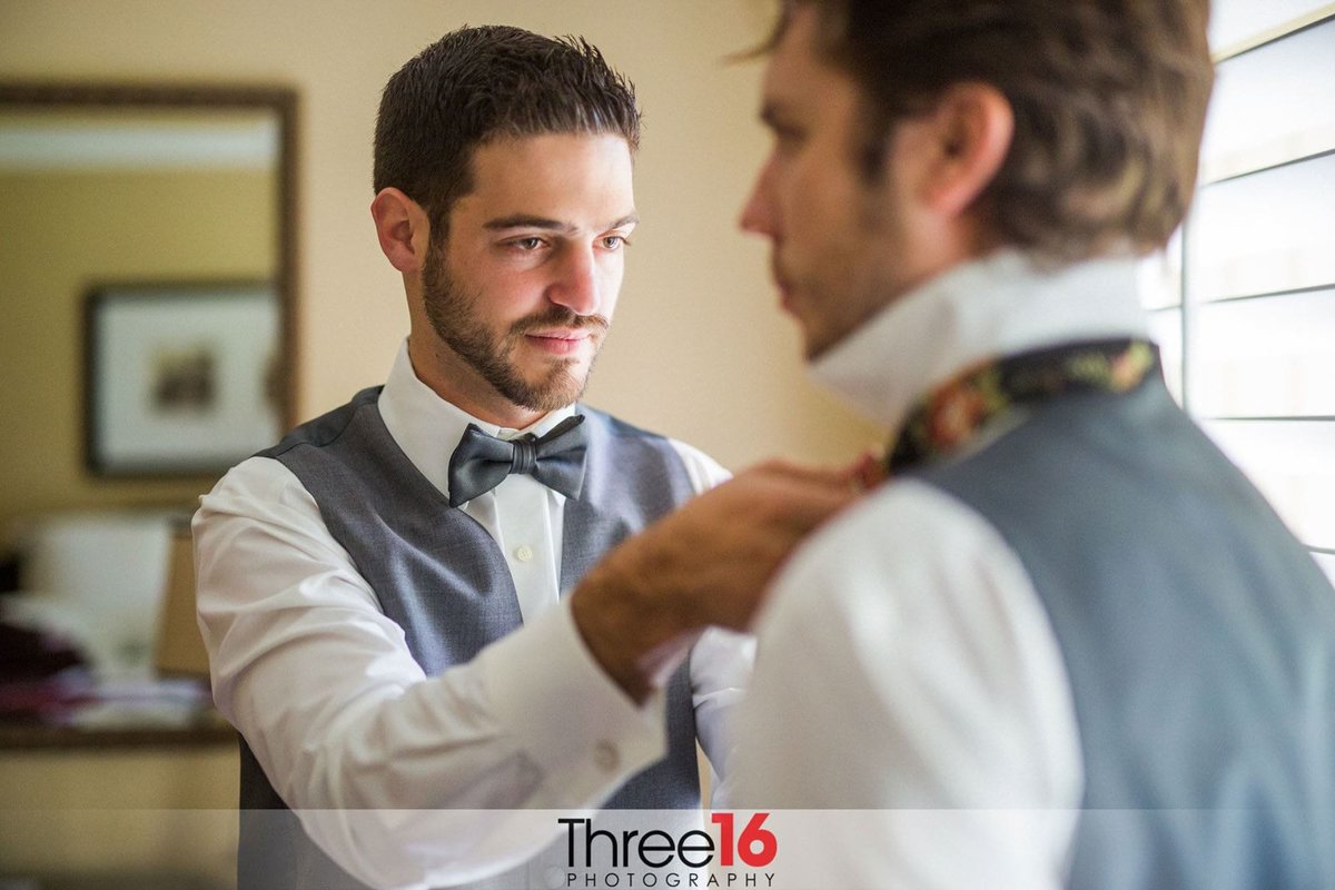 Best Man assists Groom with his tie
