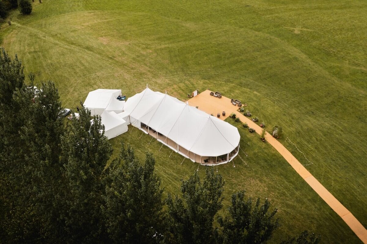 An aerial view of a large pole marquee in a field