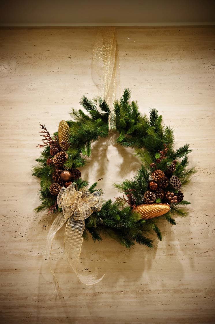 holiday wreath with gold cones, evergreens, acorns on wall for holiday party