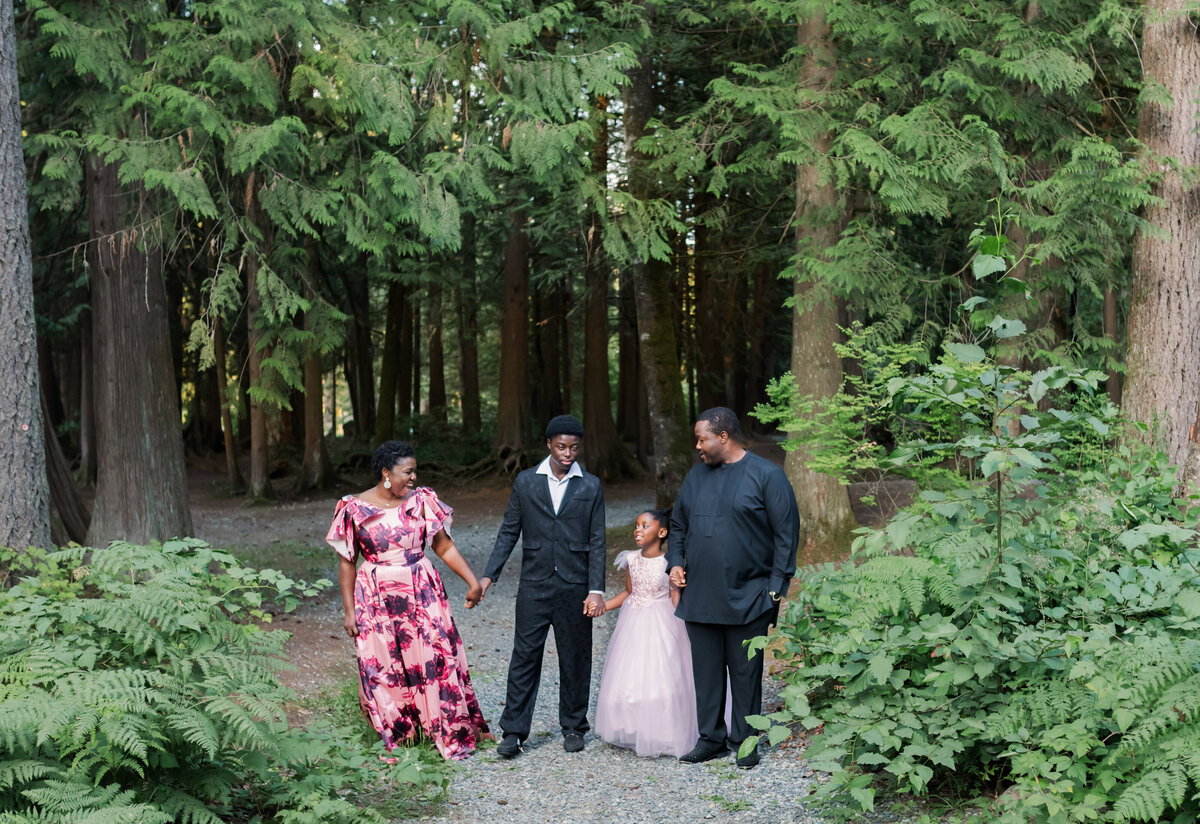 Family walking and holding hands in the forest. Dressed in fancy suits and gowns.