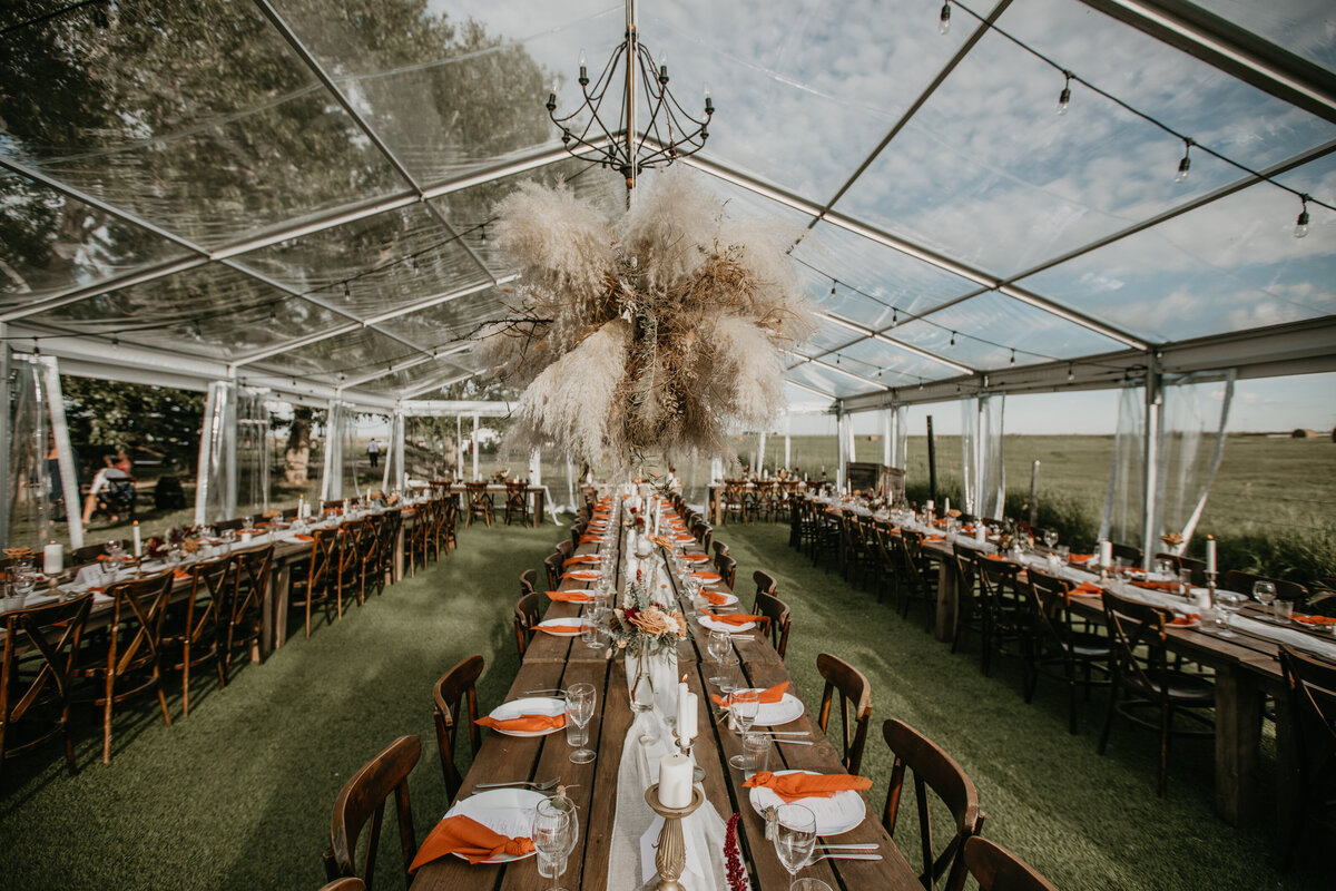 clear wedding tent with wood tables and chairs