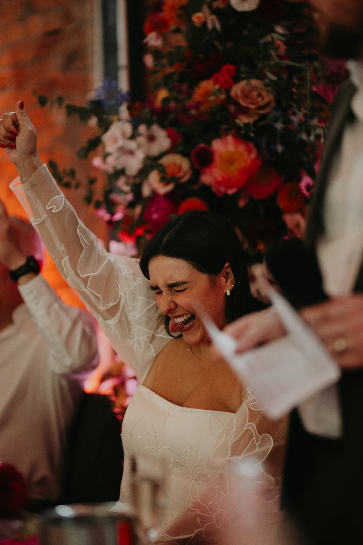 A Bride raises her hand during speeches at her wedding at Paintworks in Bristol. 