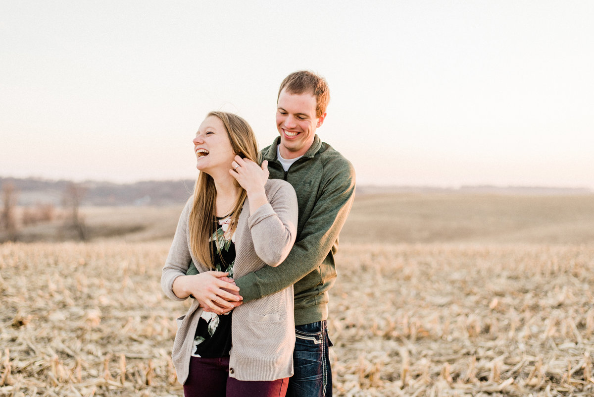 couple laughs together in iowa corn field