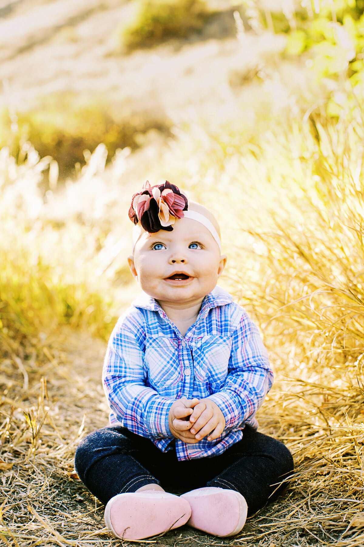 happy baby girl with bow looks up in air