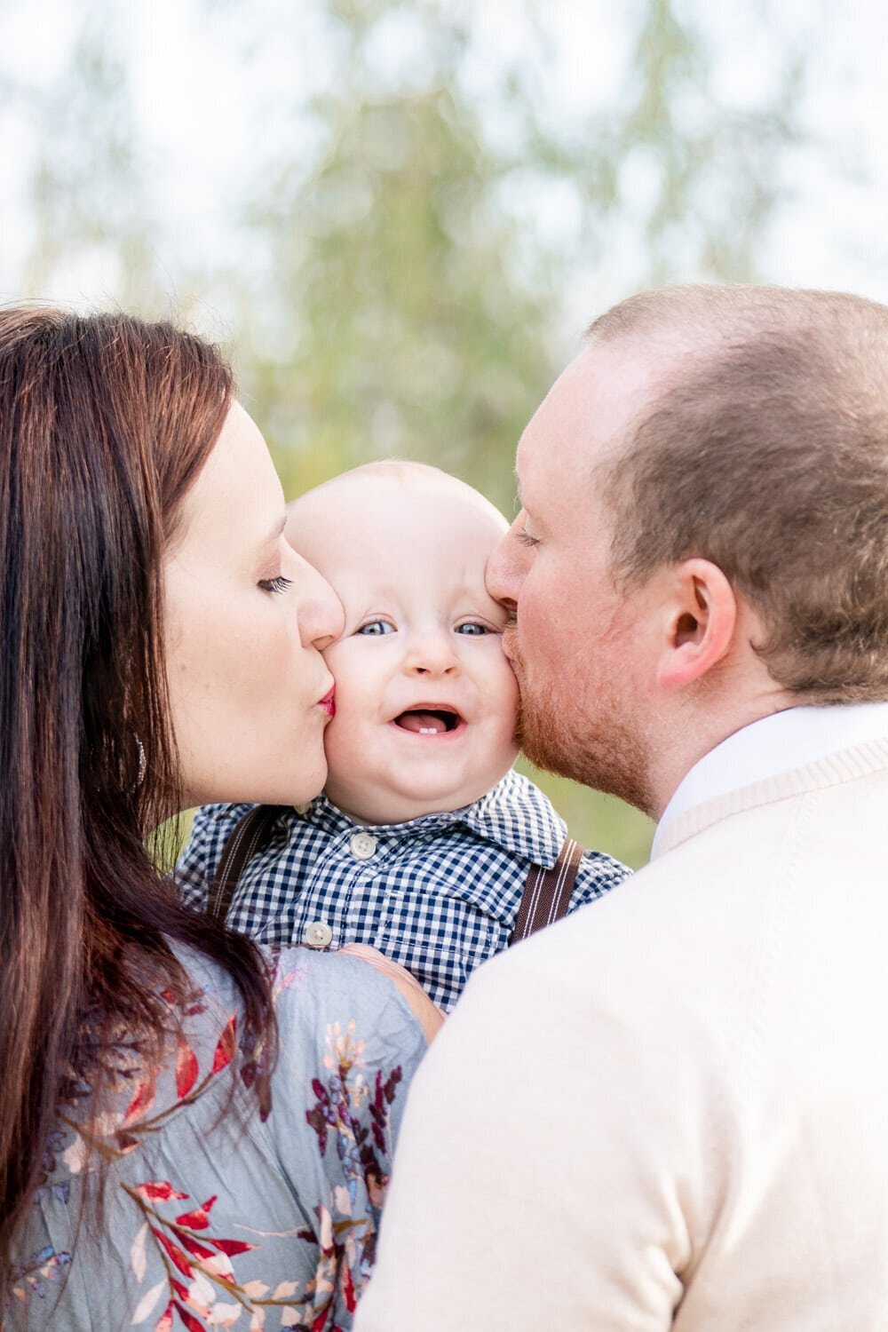 mom and dad kissing baby taken by a family photographer in Reston, VA